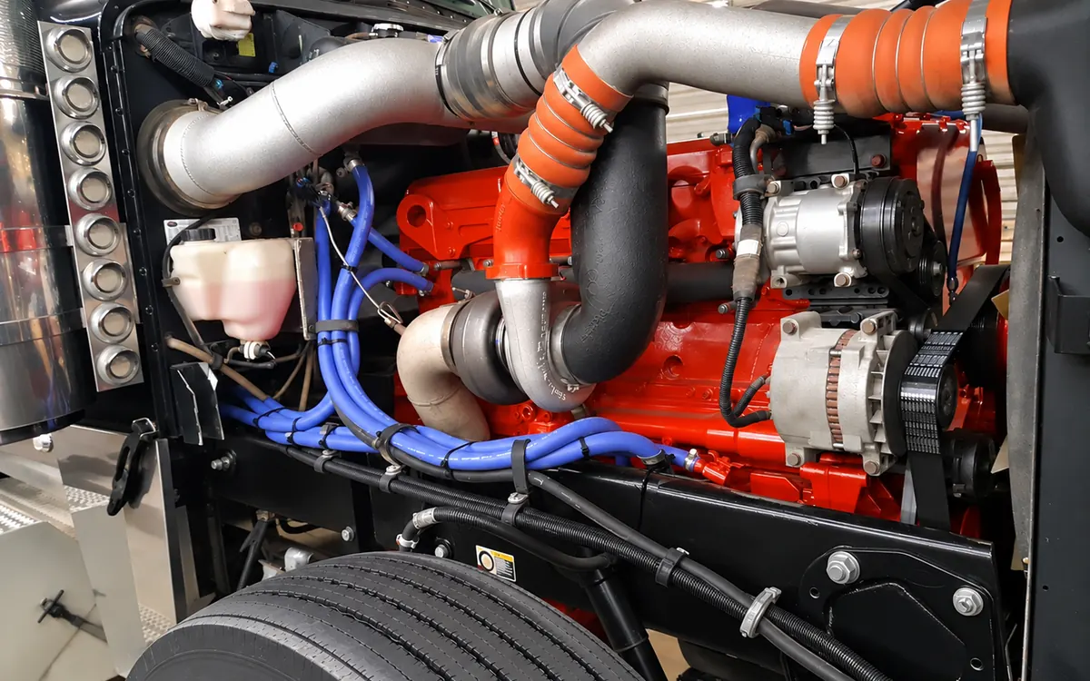 Heavy-duty diesel engine in a truck engine bay with blue silicone coolant hoses and charge air piping